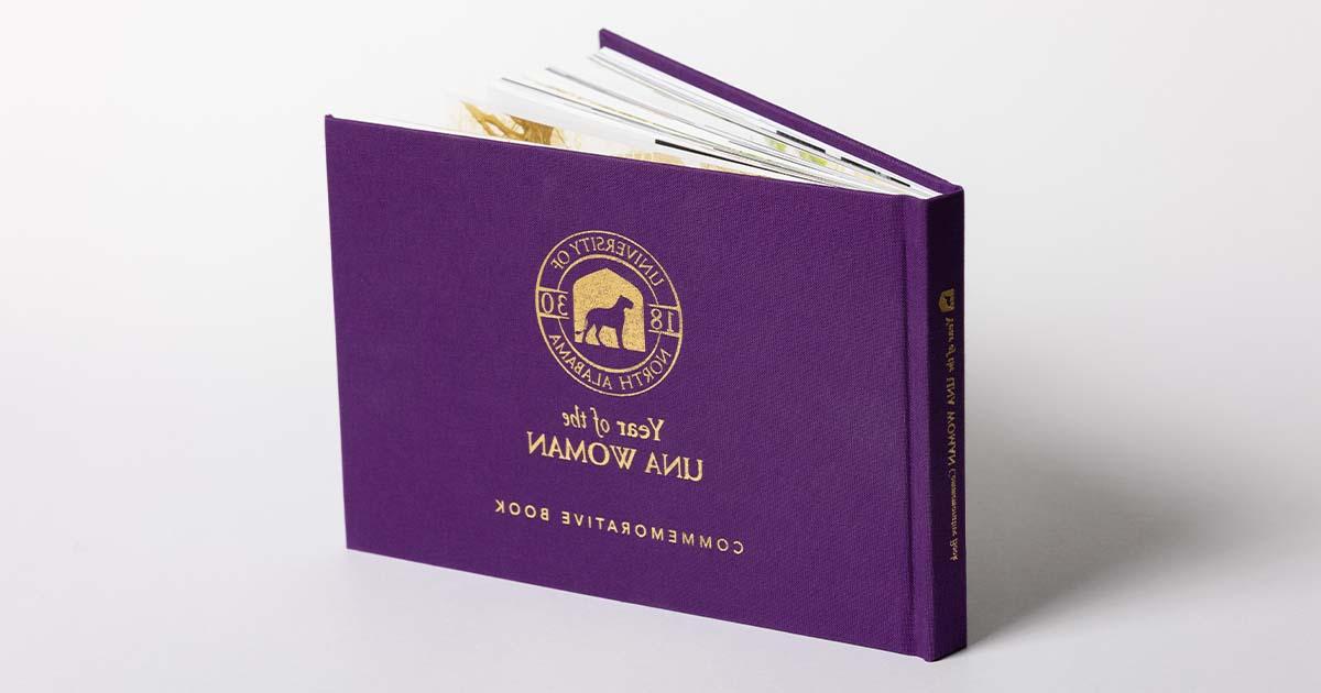 The Year of the UNA Woman Commemorative Book, a purple cloth hard-back book.